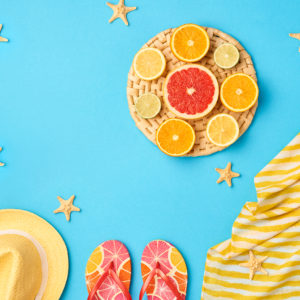 Fashion. Summer Beach set. Tropical Fruit Citrus, Orange, Lime. Bright Summer Color. Stylish woman Sunglasses, Trendy hat. Essentials creative art. Minimal concept. Top view. Yellow blue background